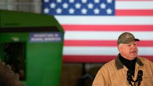 A man speaks with a U.S. flag backdrop and a green podium.